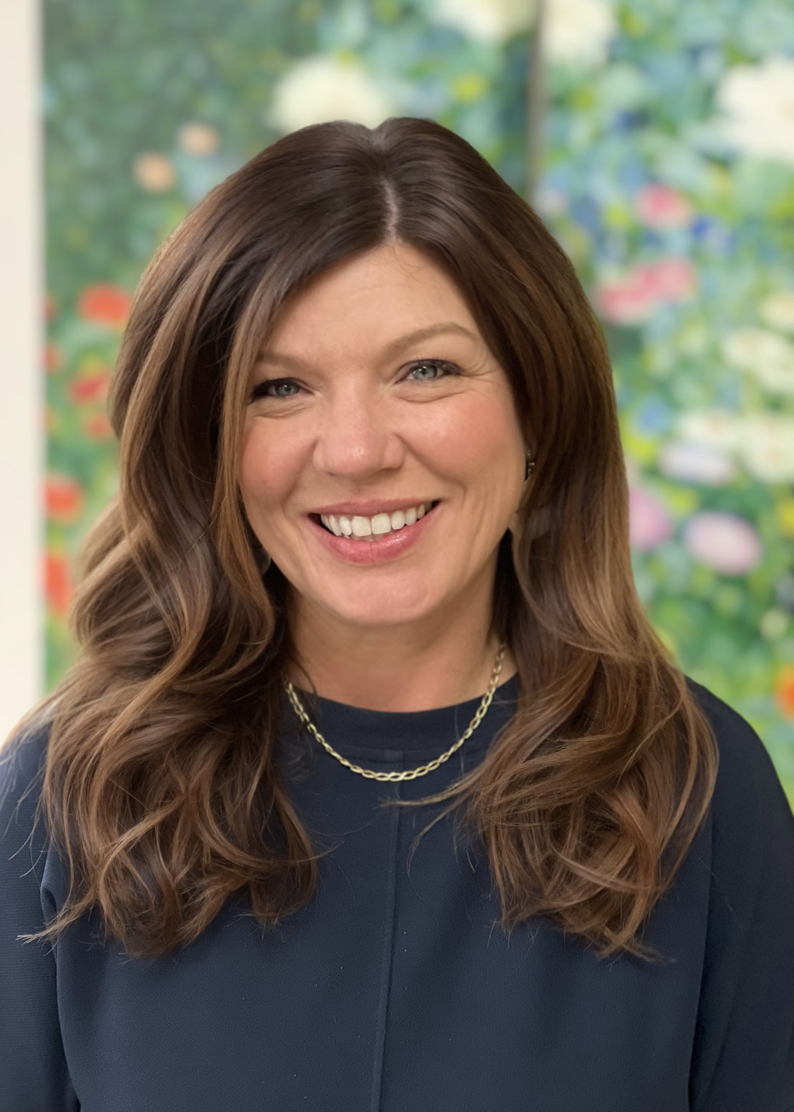 Gemini said A head and shoulders portrait photograph shows a smiling woman, who is President Rogalski, with shoulder-length, wavy brown hair,